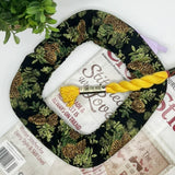 Roll of white fabric with yellow thread on a black fabric with green pattern