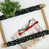 Scroll frame grime guard with fabric highlighted by holly and musical notes. on black background.