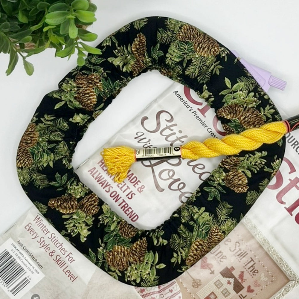 Roll of white fabric with yellow thread on a black fabric with green pattern