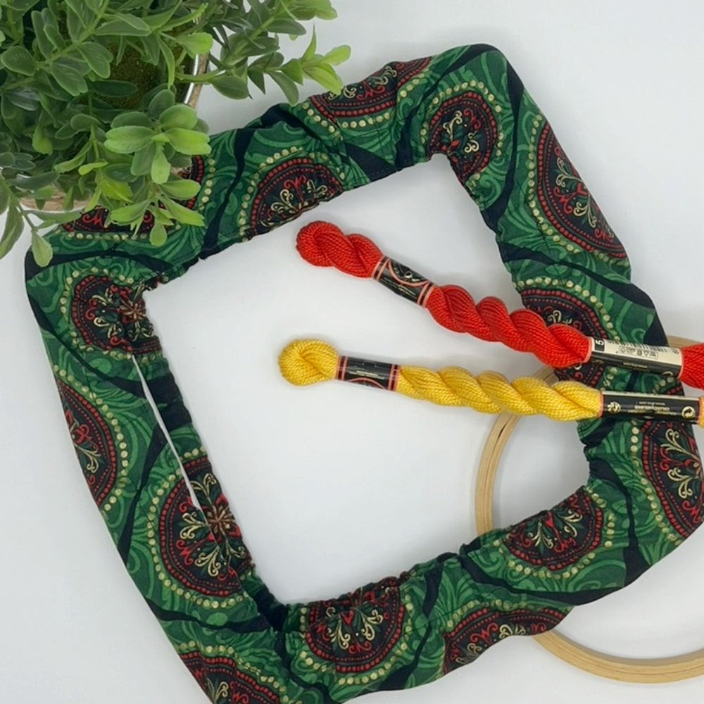 Embroidery hoop with colorful christmas theme medallions in green accented with red medallions.