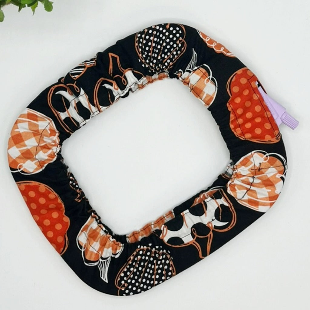 Halloween-themed toilet seat cover with pumpkins and ghosts on a white background
