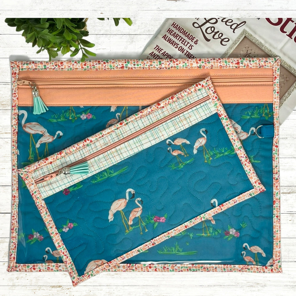 Floral-patterned fabric with flamingo design on a blue background, displayed on a wooden surface.