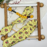 Yellow floral-patterned fabric on a wooden scroll frame with a white background