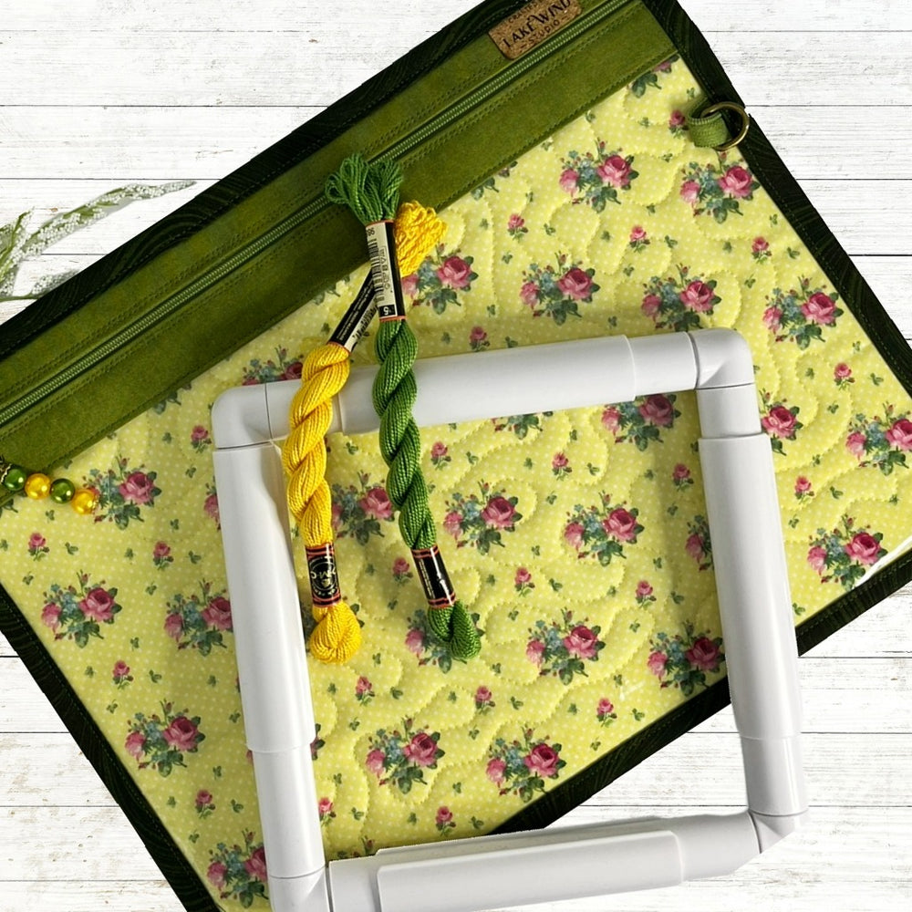 Embroidery hoop with yellow and green thread on a floral fabric mat